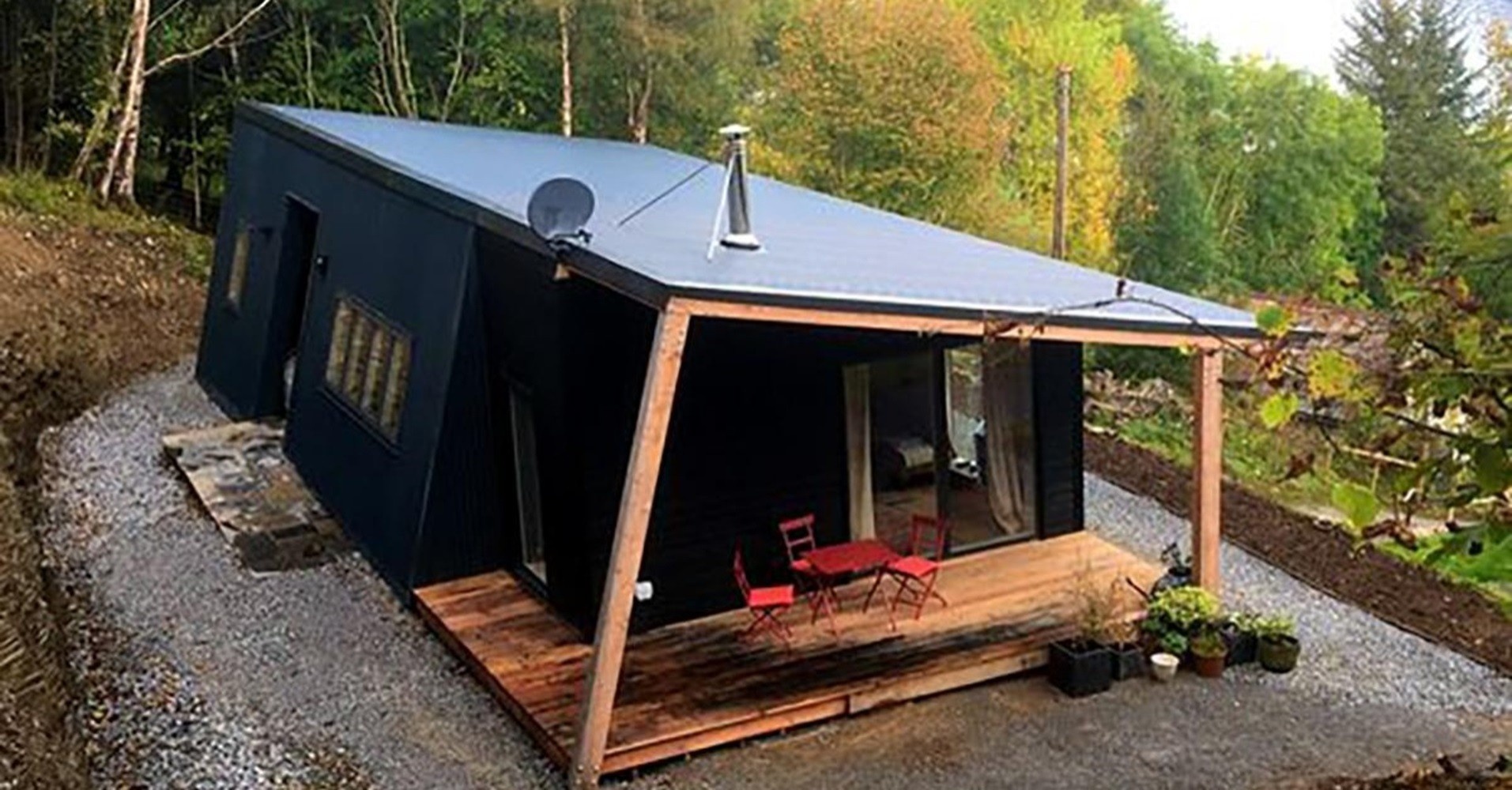Small off-grid style cabin with a timber deck set among trees